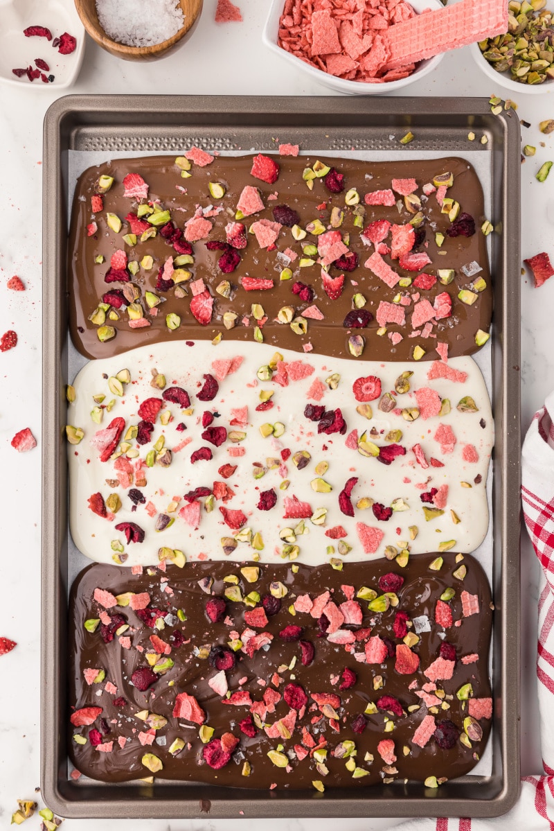 Melted chocolate with berry and nuts sprinkled on top of it to make candy bark 