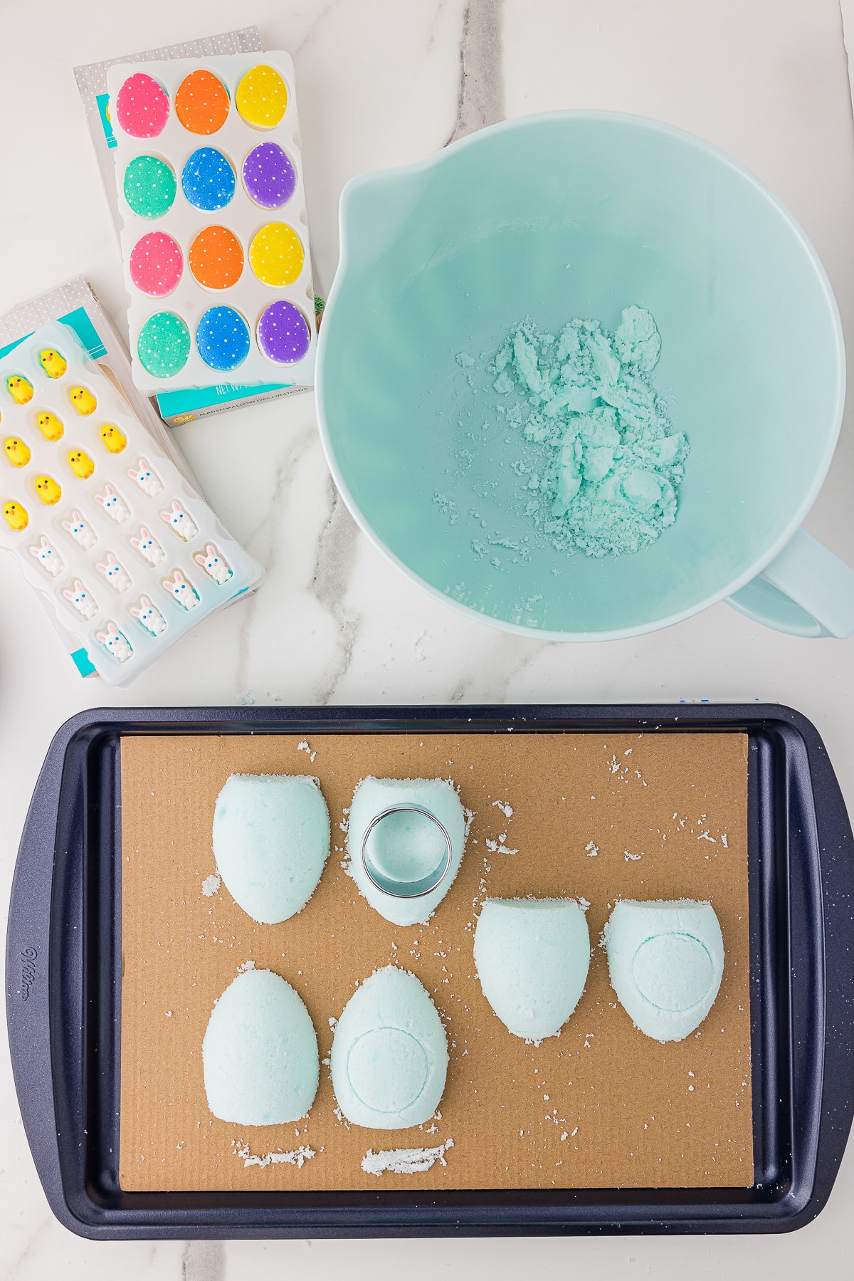 Homemade light blue sugar eggs on a baking sheet with Easter candy and decor