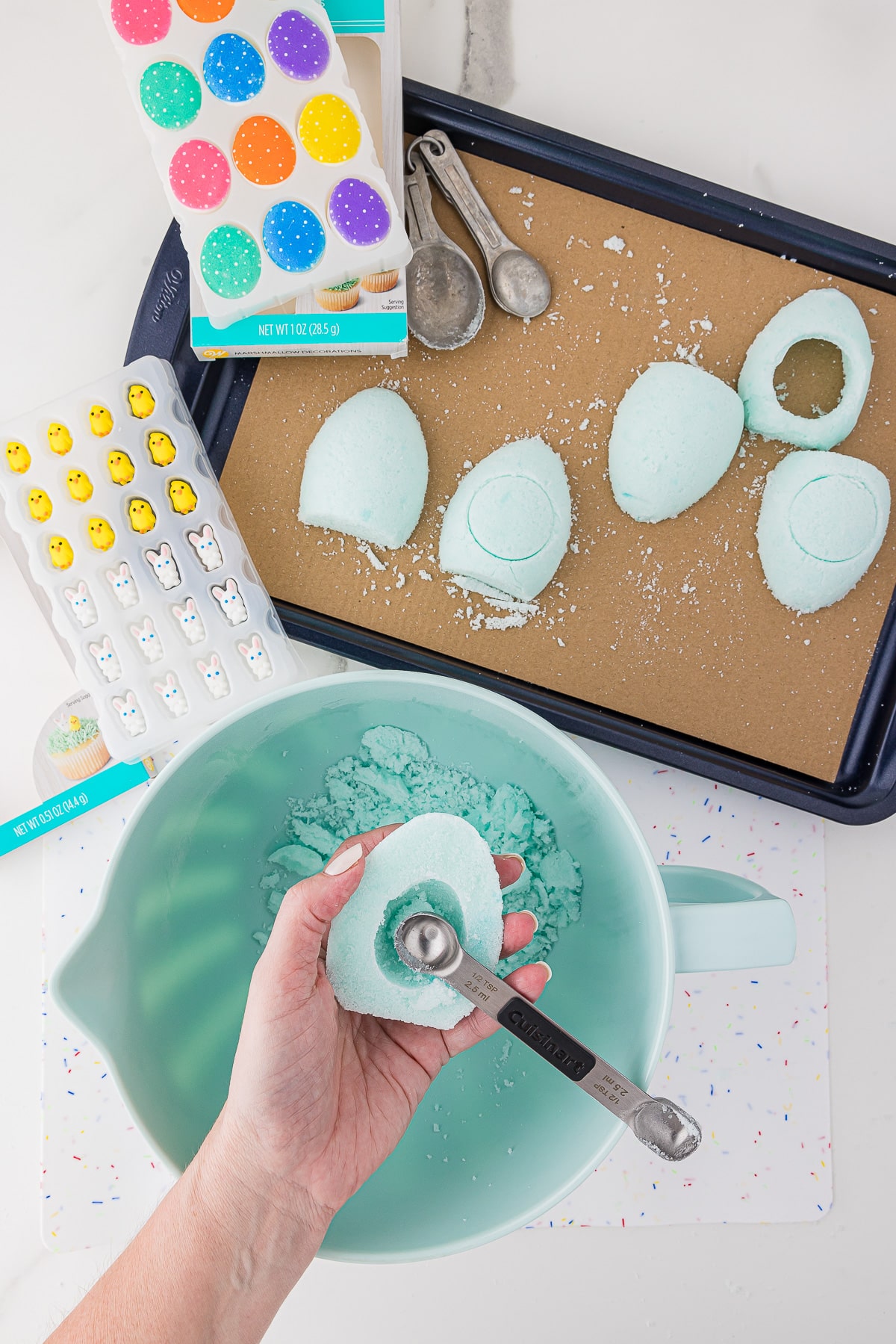A hand carving out the middle of a sugar egg mold demonstrating how to make panoramic Easter eggs