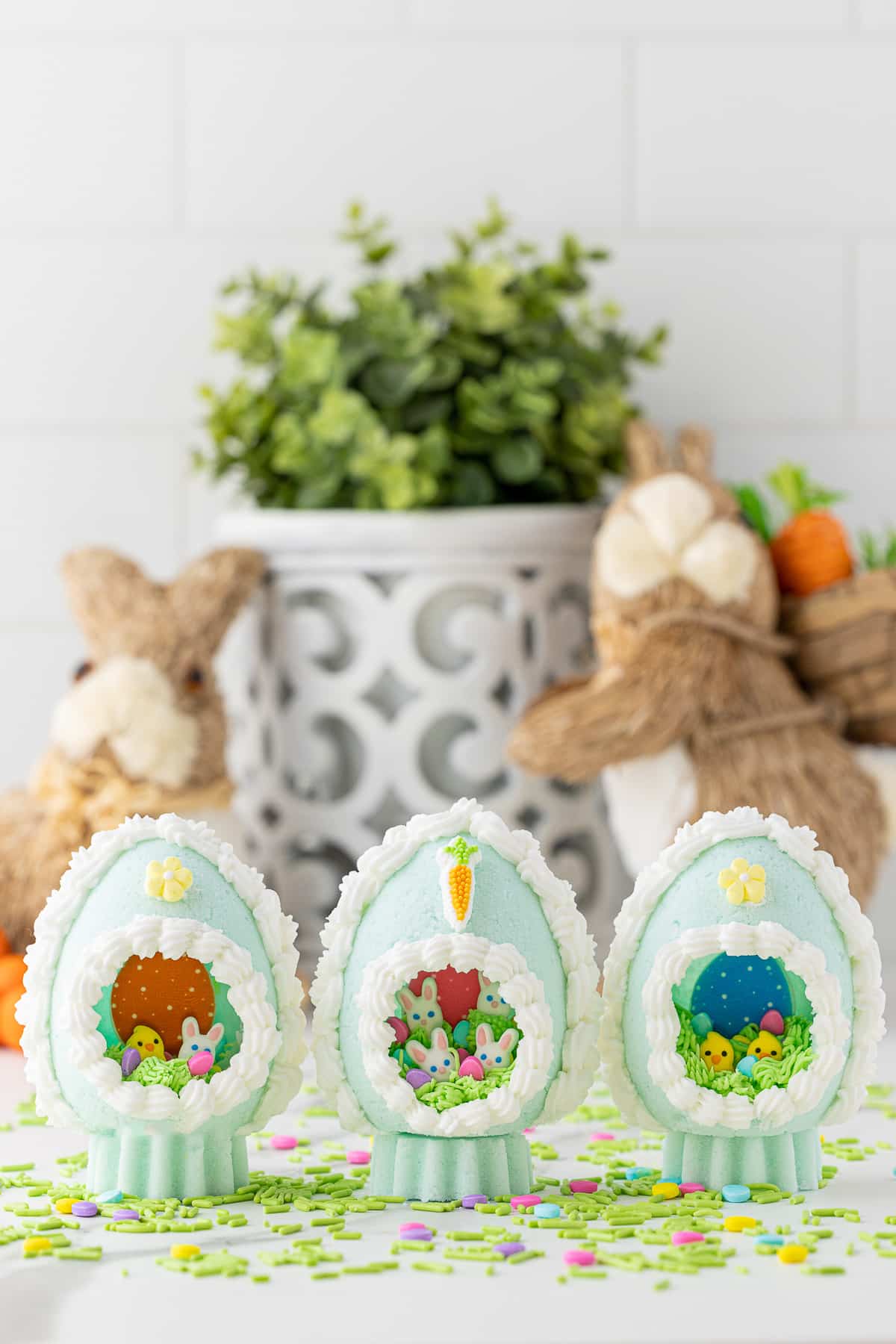 Easter sugar eggs with a plant and two Easter bunnies in the background