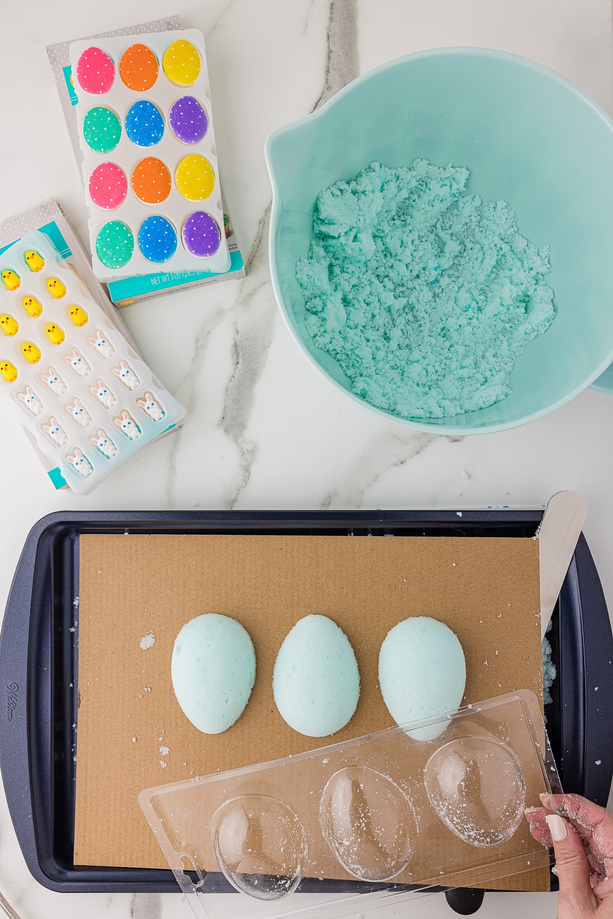 Sugar eggs and molds on a baking sheet with Easter candy decorations