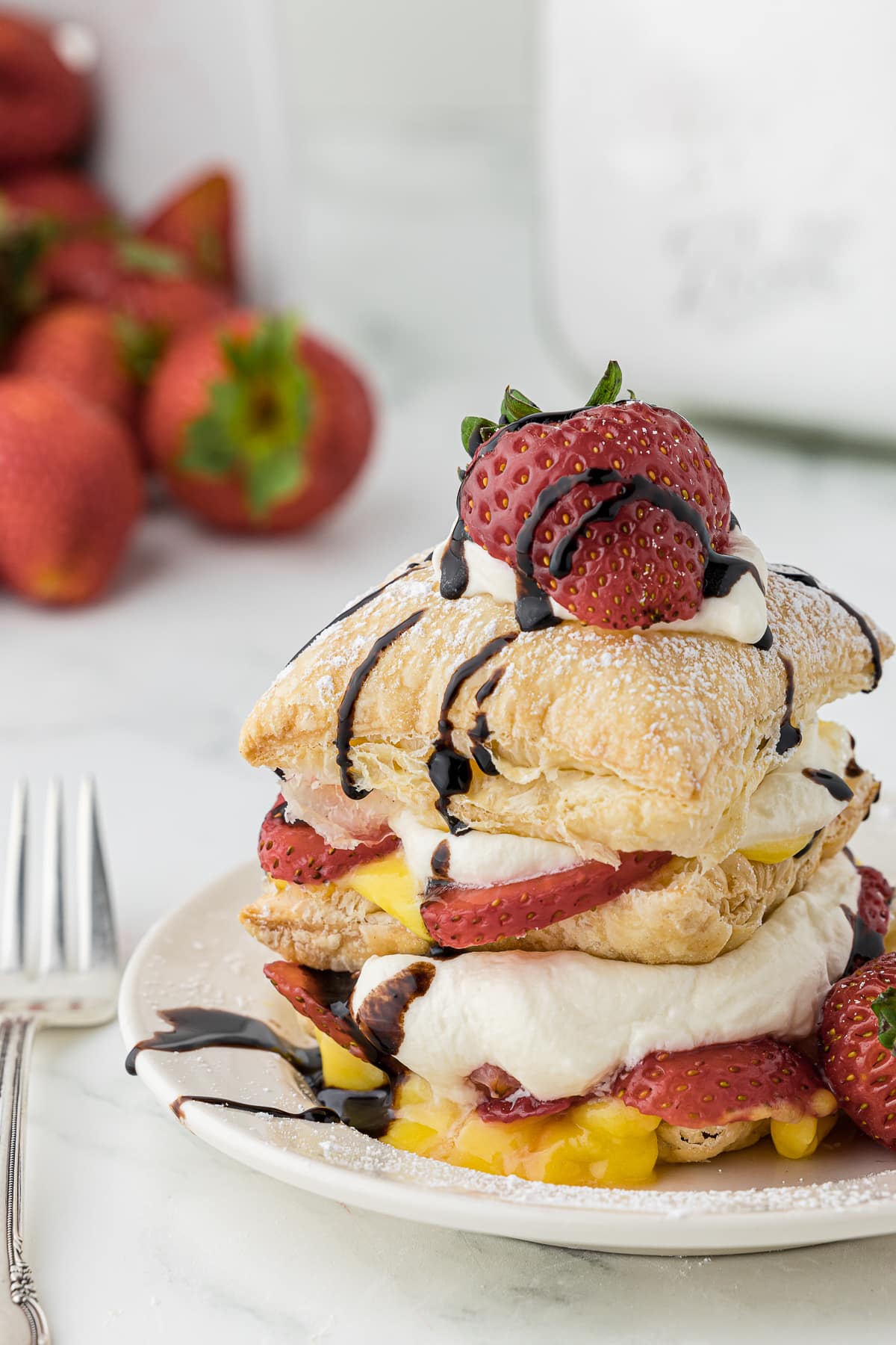 A single serving of homemade strawberry napoleon dessert with powdered sugar and drizzled chocolate