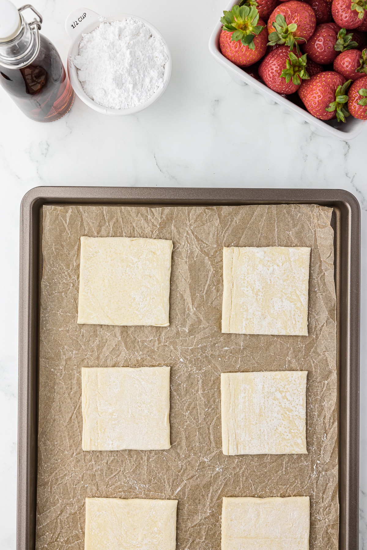 Puff pastry squares on a baking sheet with parchment paper