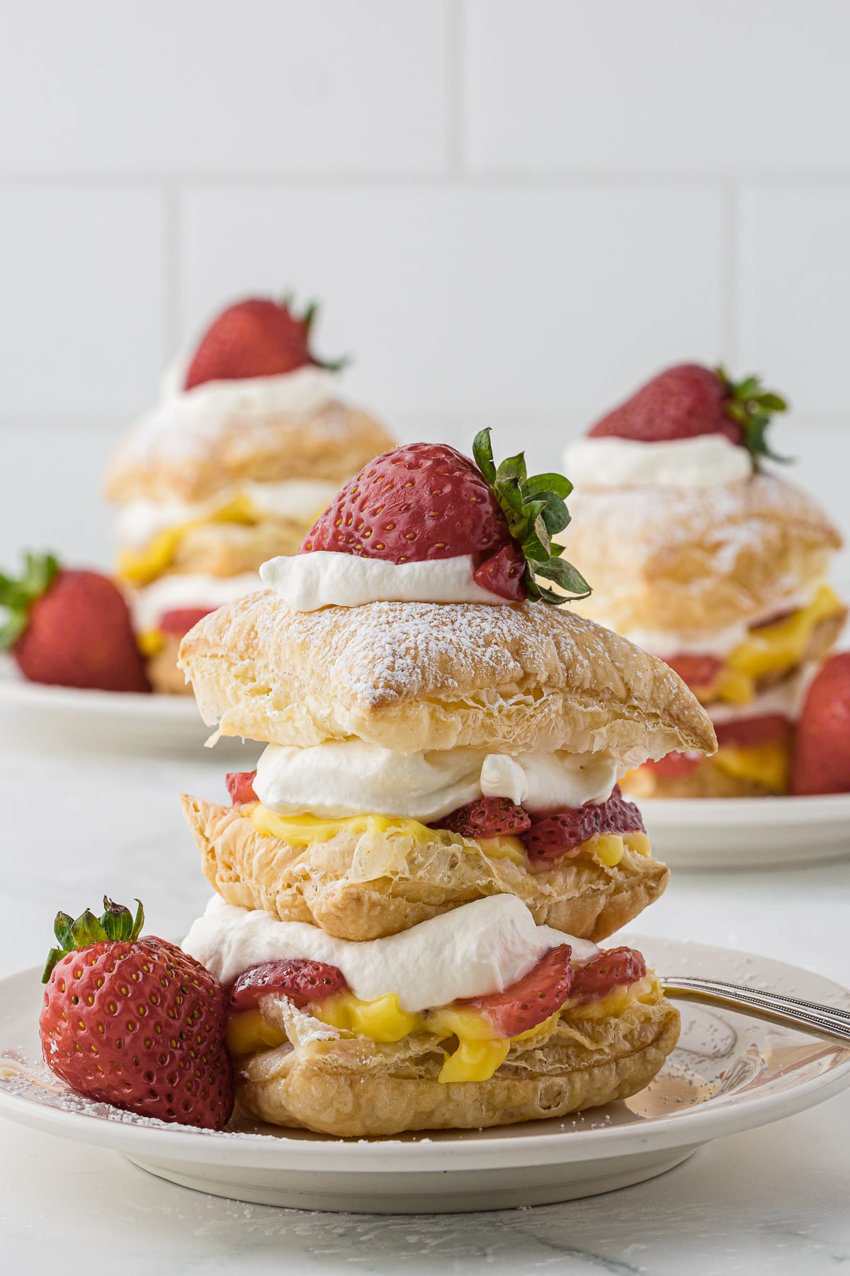 3 plated servings of Strawberry Napoleon desserts with fresh strawberries