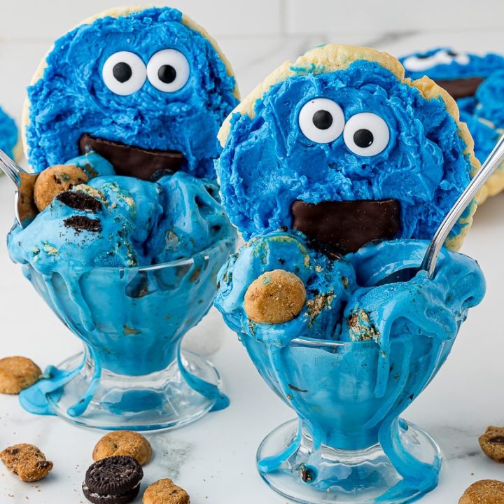 Two bowls of blue ice cream with cookie monster cookies and little mini chocolate chip cookies sprinkled around them