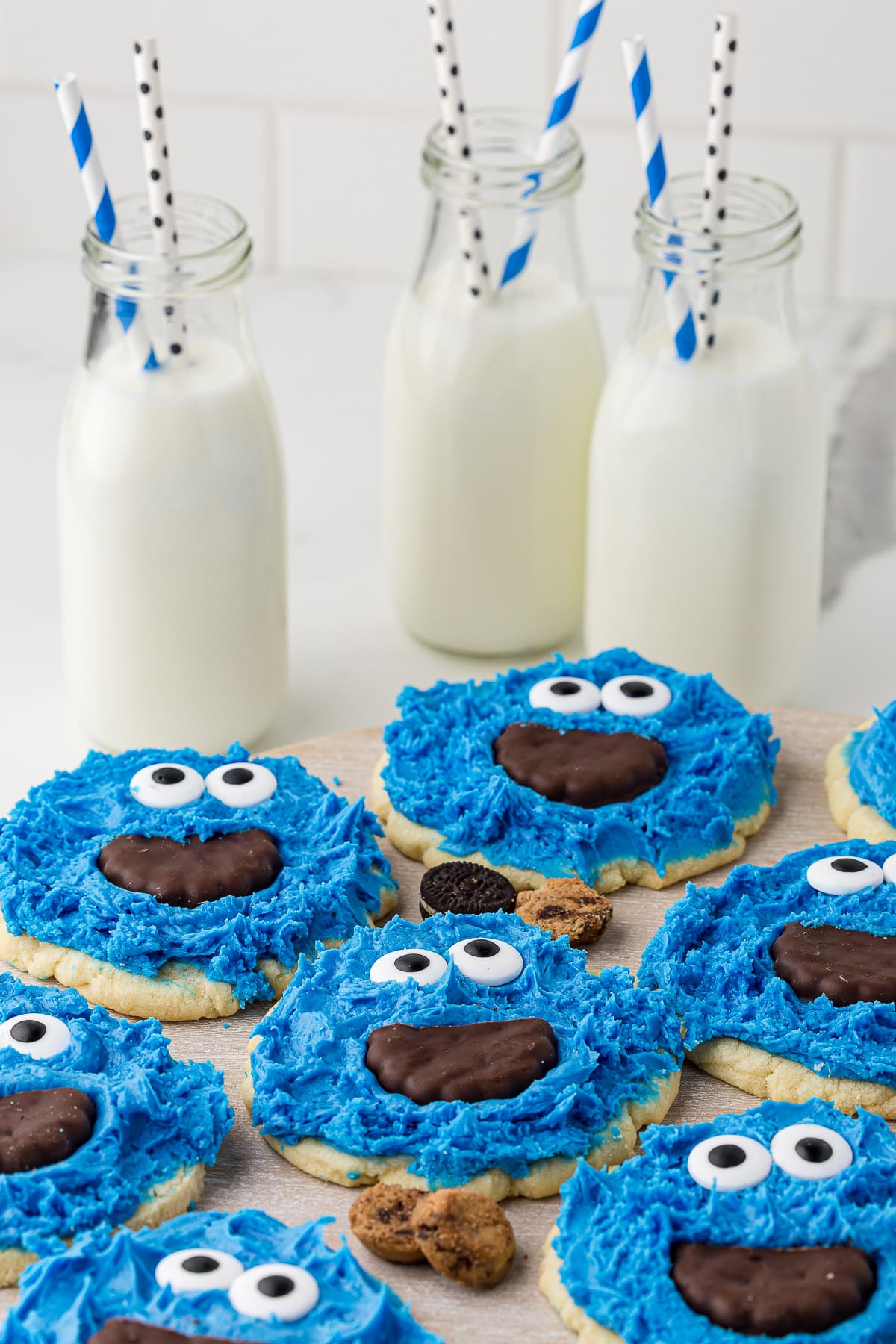 cookie monster themed cookies on a white background with glass milk bottles