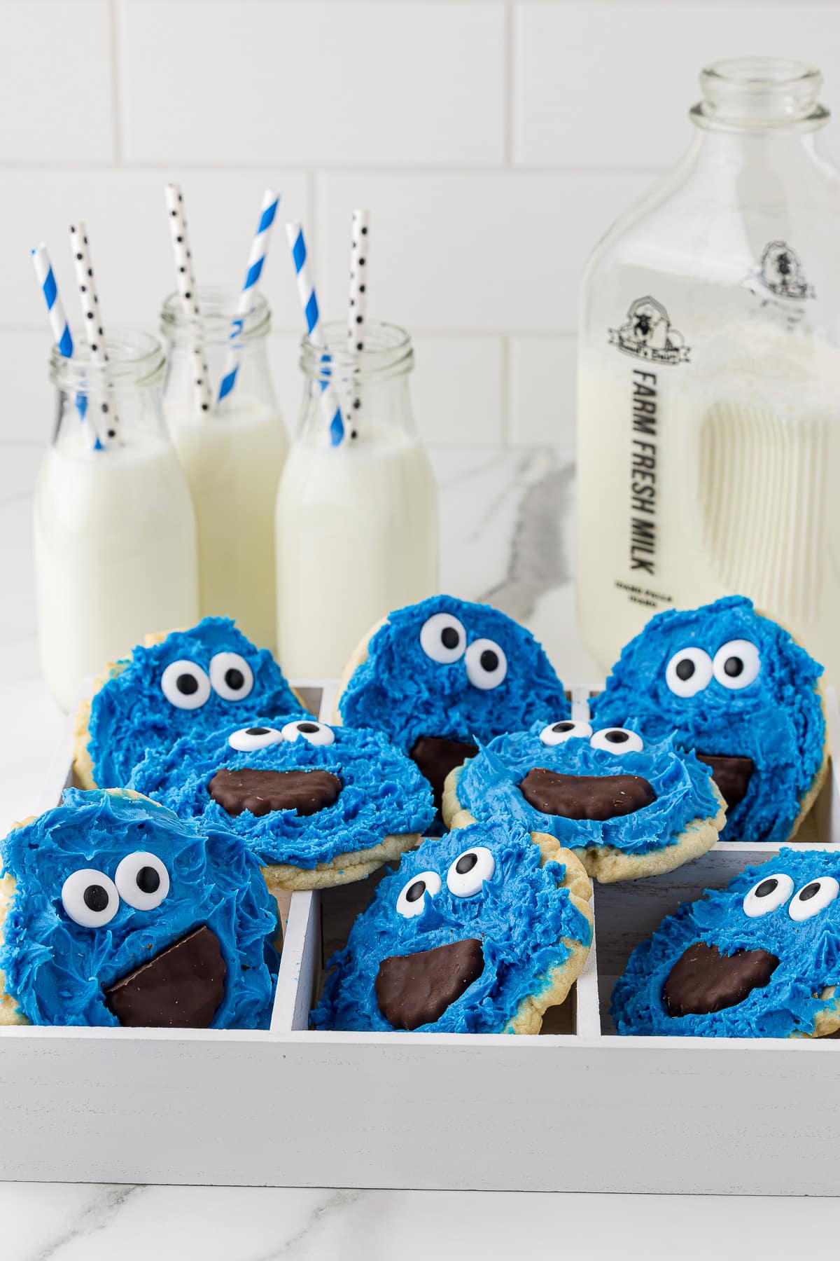 cookie monster decorated cookies in a white box with milk in the background