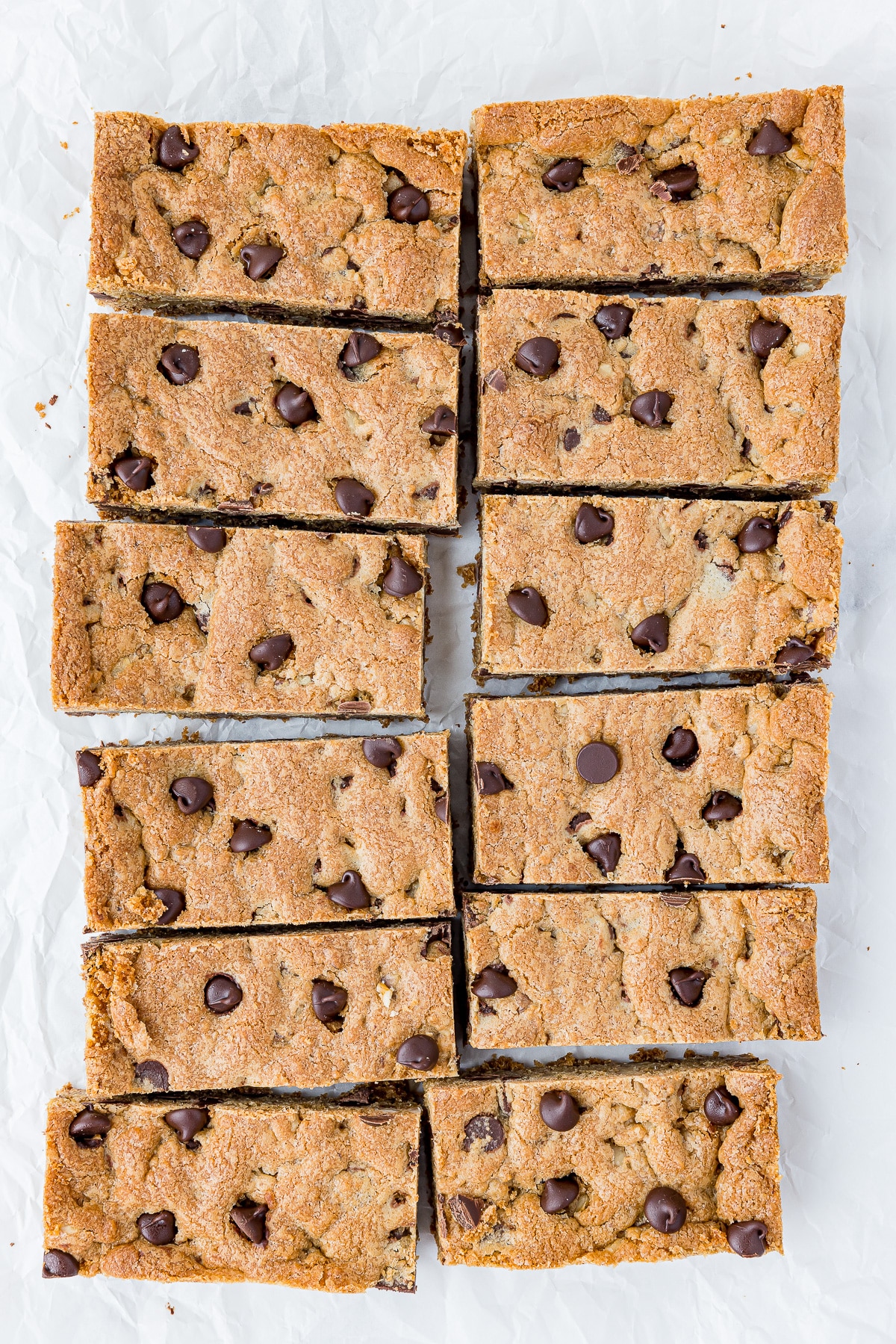 12 chocolate chip cookie bars on a white piece of crumpled parchment paper