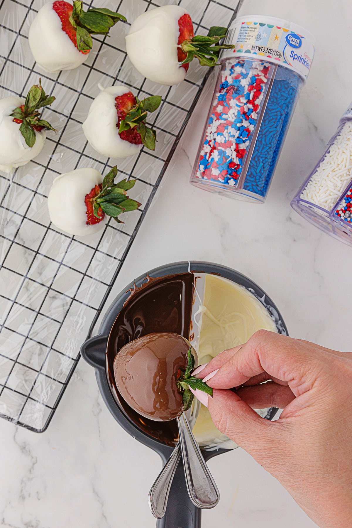 Dipping strawberries in either dark or white chocolate, and bottles of edible red, white and blue sprinkles and stars
