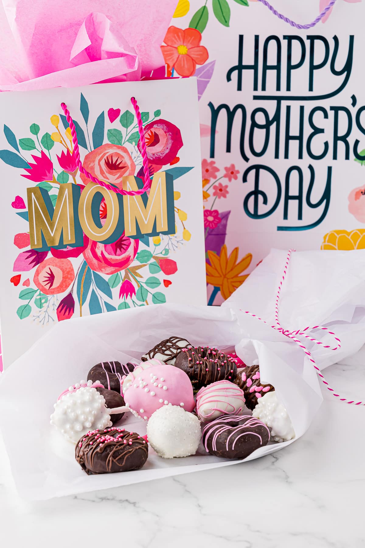 A bouquet of chocolate treats laying in front of Mother's day gift bags
