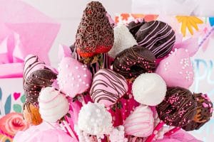 Close up of chocolate covered strawberries in a bouquet with party bags and decor in the background