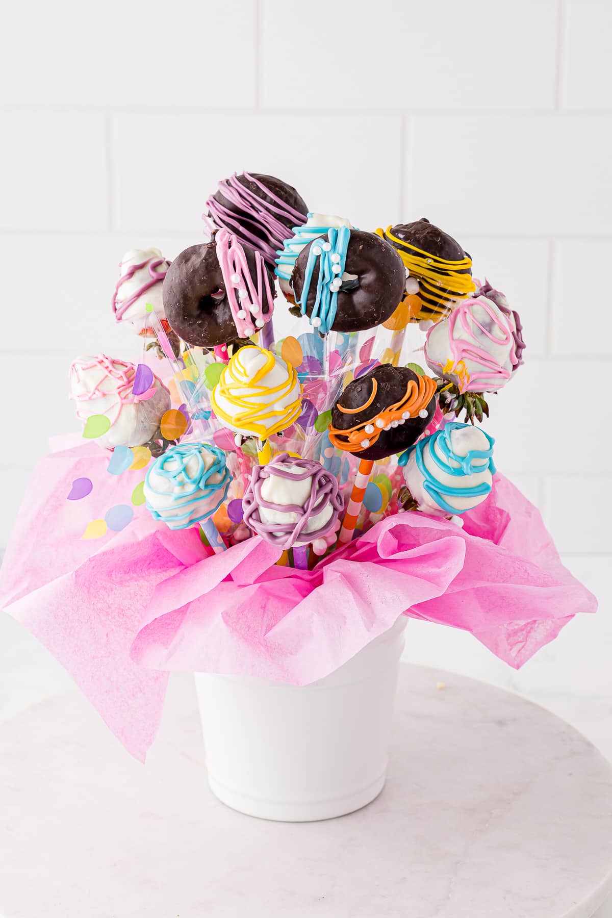 Beautiful treat bouquet in a white bucket with pink tissue paper with a white background
