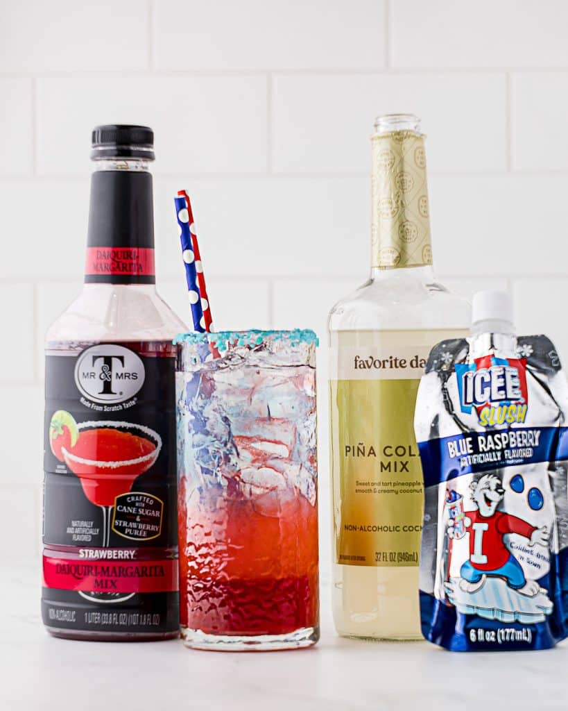 Red, white and blue layered drink in tall glass with two straws and pop rock like candy around entire upper rim of glass; consisting of daquiri margarita mix, pina colada mix and blue raspberry icee.