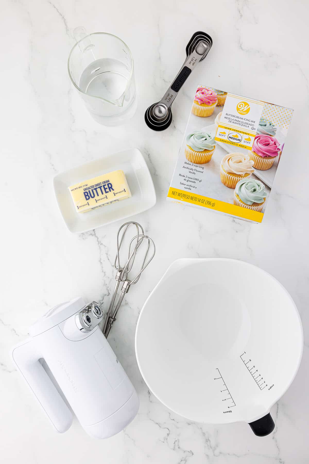 Wilton buttercream frosting kit and a mixer, mixing bowl and a stick of butter on the counter