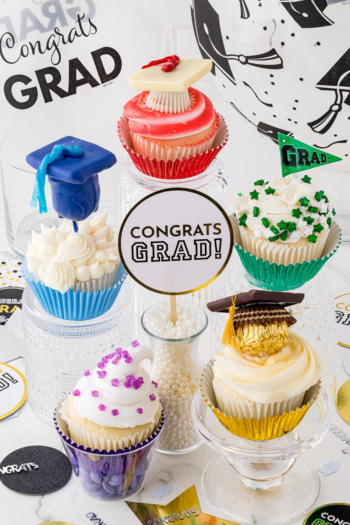 A grouping of graduation themed cupcakes with a Congrats Grad! sign in the middle