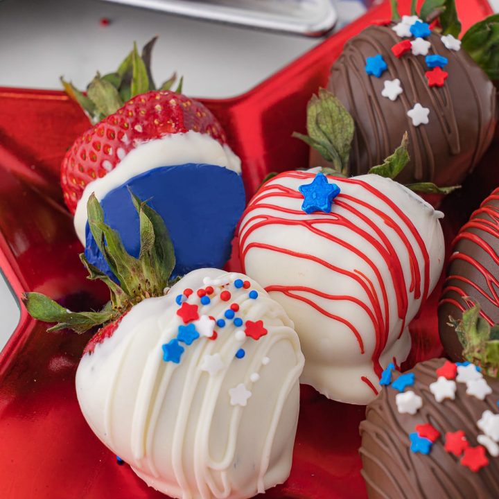 White chocolate and dark chocolate covered strawberries with edible sprinkles, stars and striping, plated on a red star-shaped plate and a silver star-shaped plate