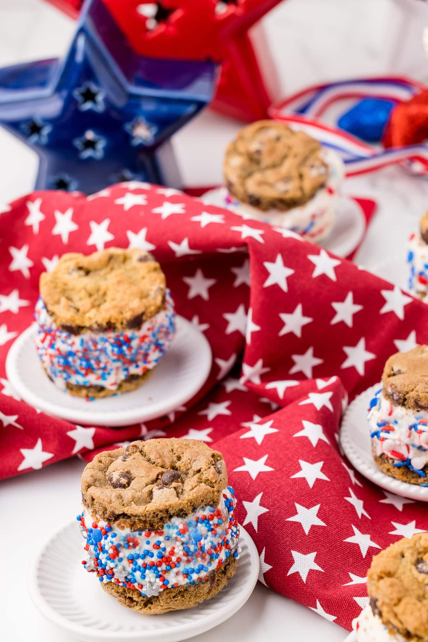 five 4th of july cookie sandwiches on white plates with red napkins and a red star and blue star in the background