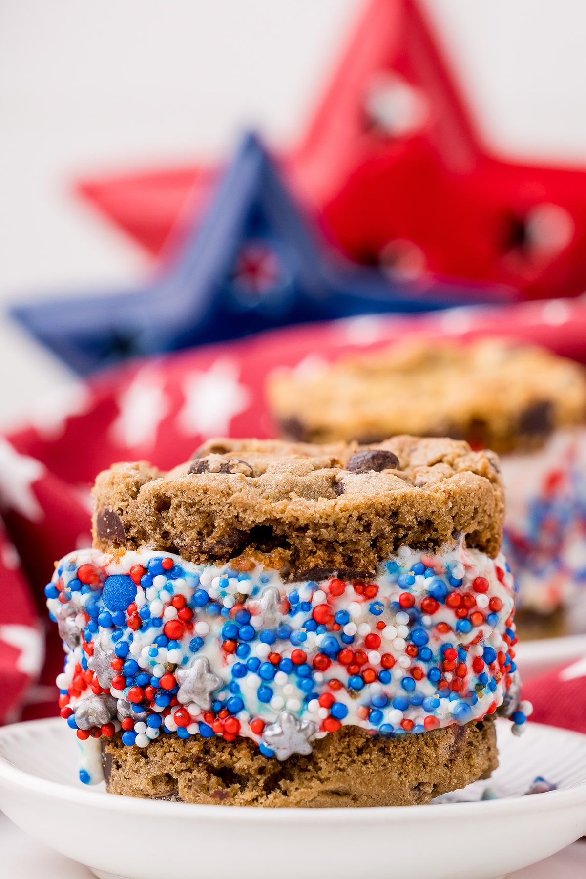 a 4th of july sandwich cookie with red, white, and blue sprinkles on the ice cream
