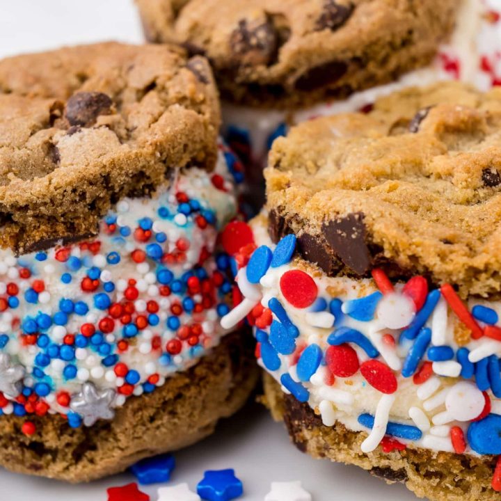 three red white and blue sprinkled ice cream cookie sandwiches on a white plate