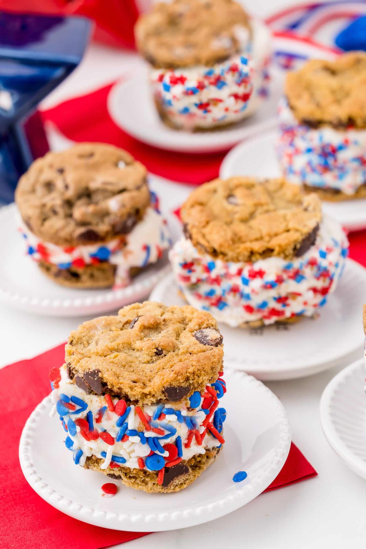 five 4th of july cookie sandwiches on white plates with red napkins