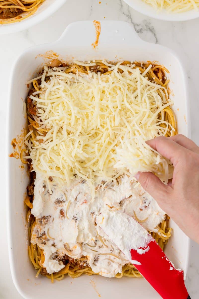 white baking dish with spaghetti, and grated mozzarella