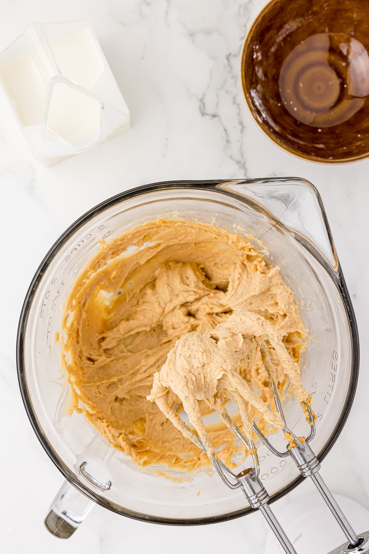 peanut butter filling in a glass batter bowl with kitchen aid mixer on a white countertop
