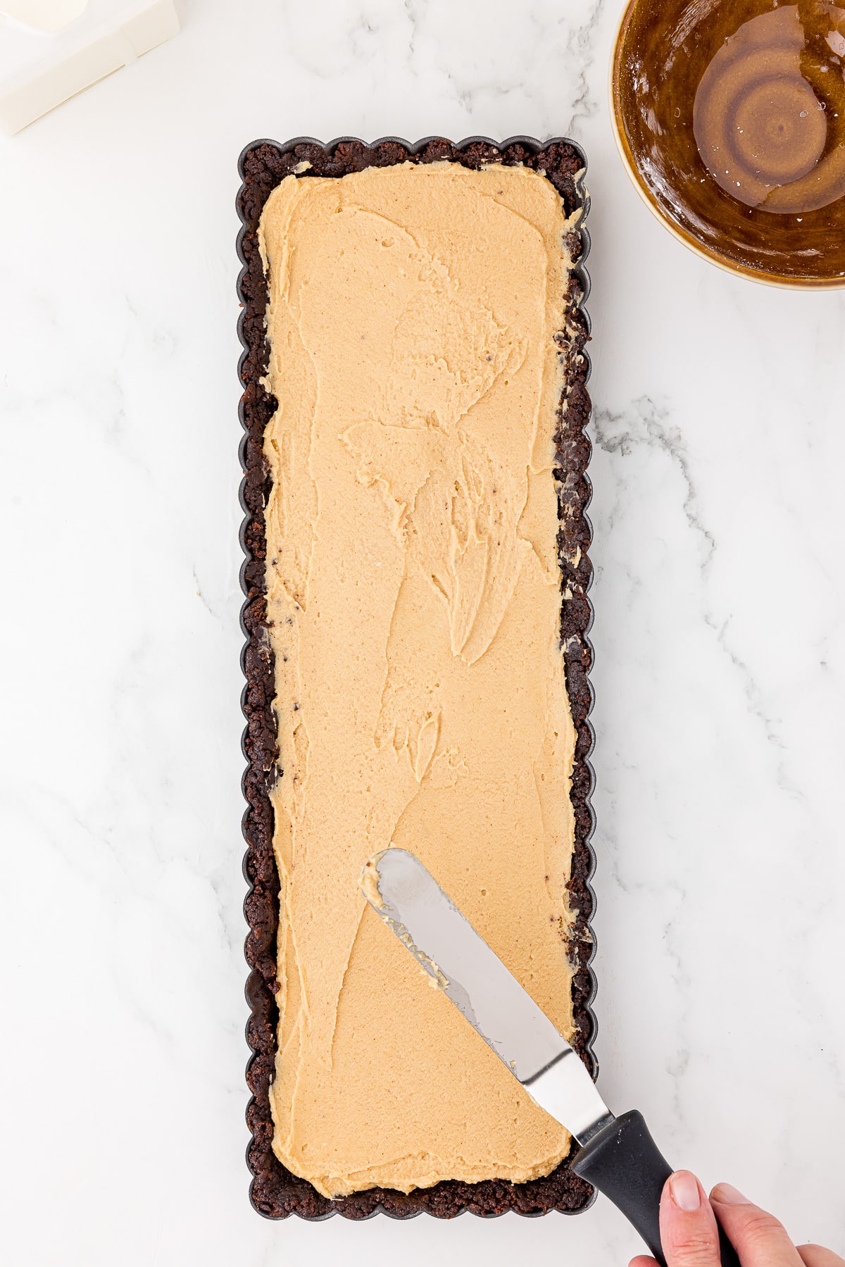 spreading peanut butter filling on a chocolate tart shell