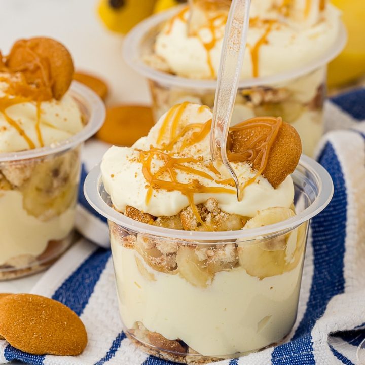 Several layered pudding cups topped with caramel drizzle, bananas and nilla wafers