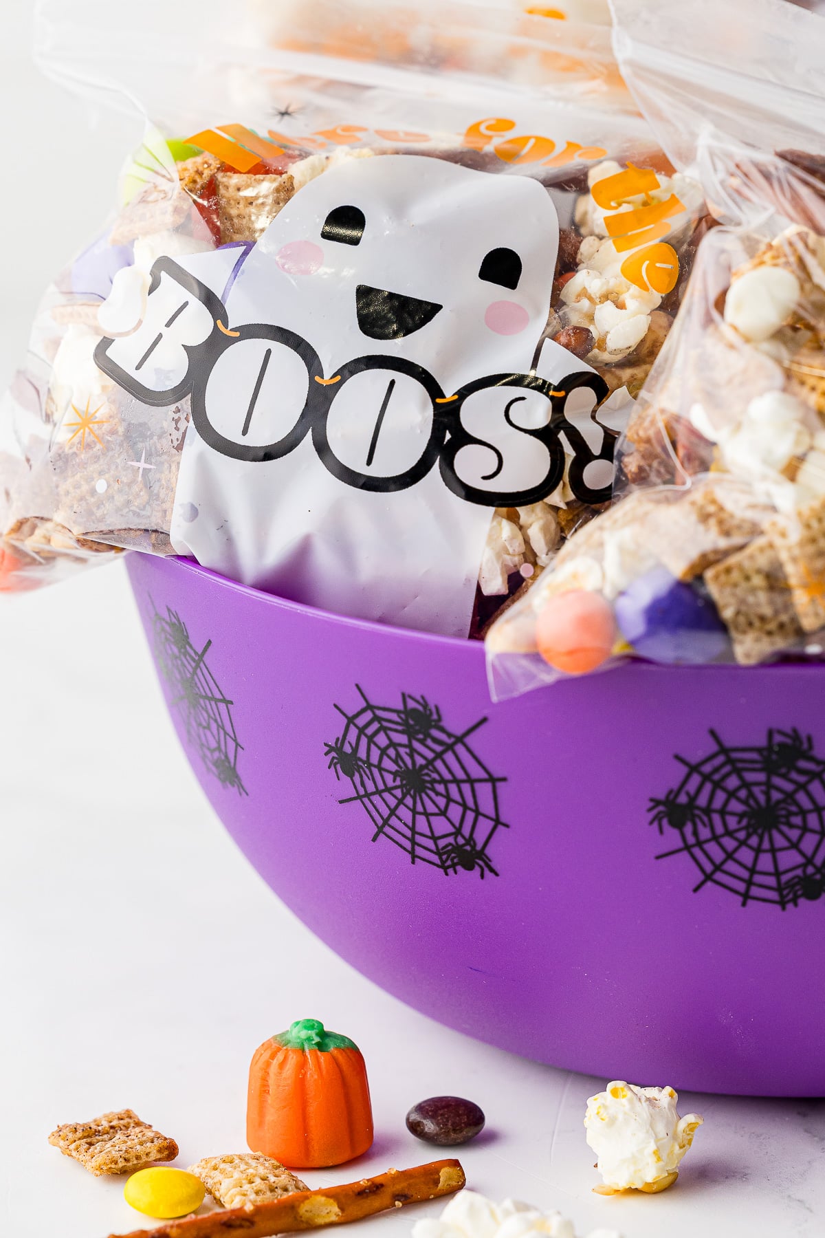 halloween treat bag filled with chex mix in a purple bowl with spiderweb decorations