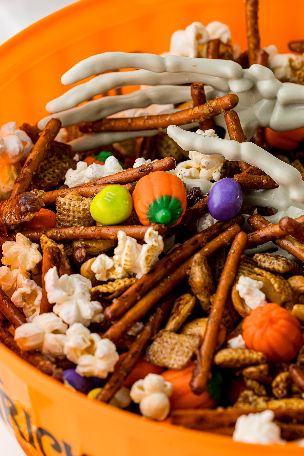 closeup of halloween chex mix with skeleton hands inside