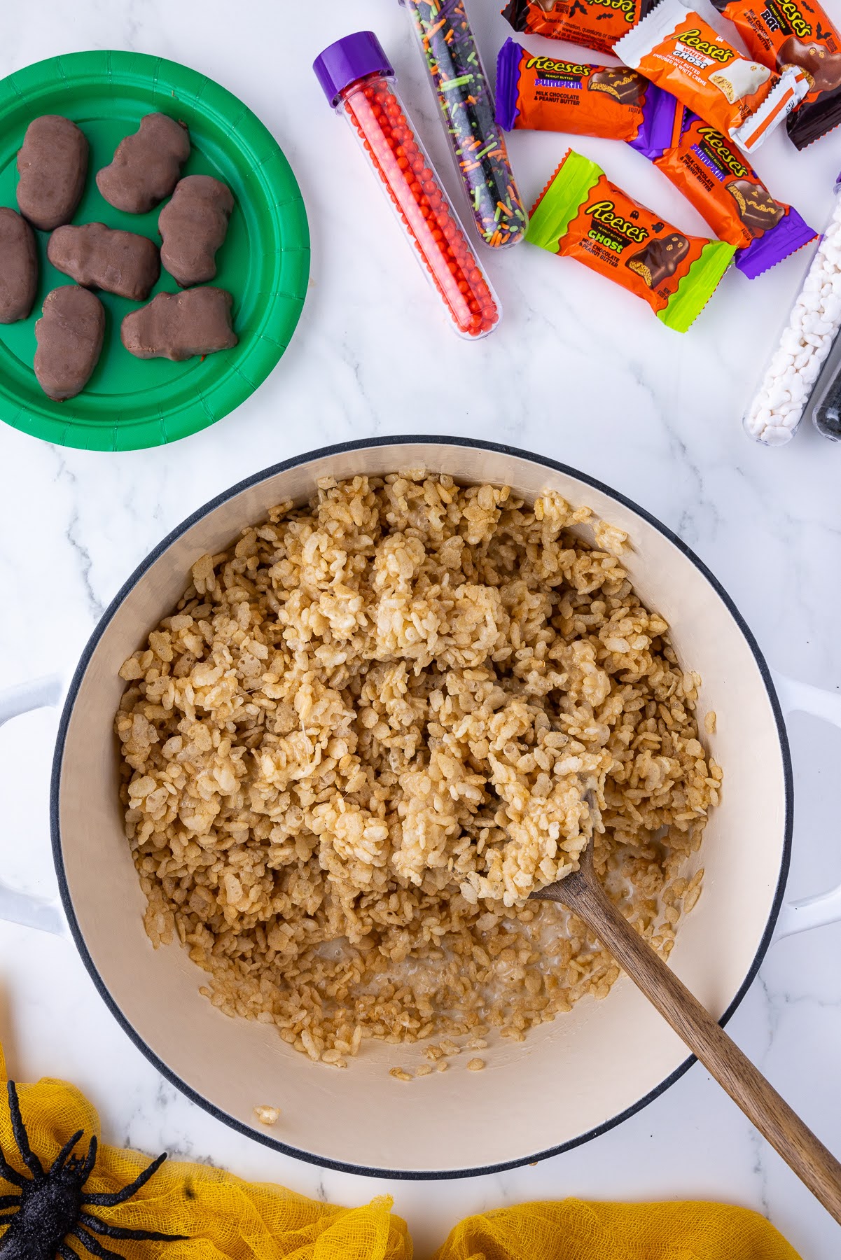 pot of rice crispies with a wooden spoon and wrapped chocolates in the background