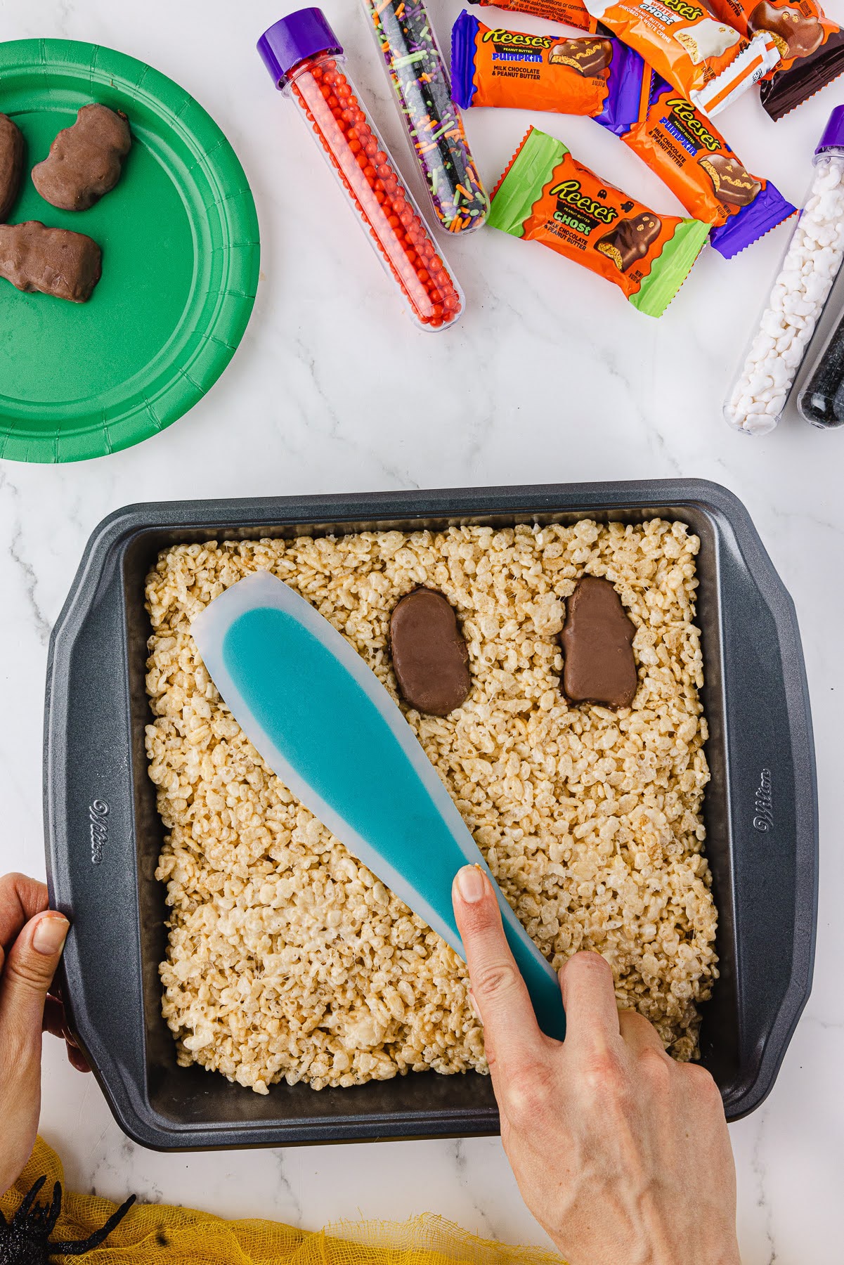 square wilton pan with a blue spatula with candy wrapped in the background