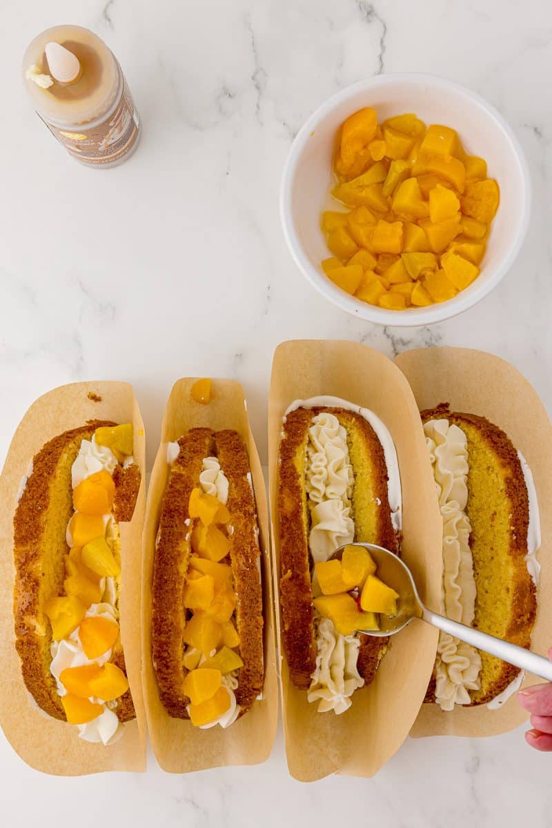 spooning sliced peaches onto cake tacos filled with cream cheese