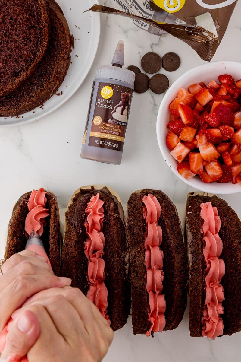 piping strawberry cream cheese onto four chocolate cake tacos