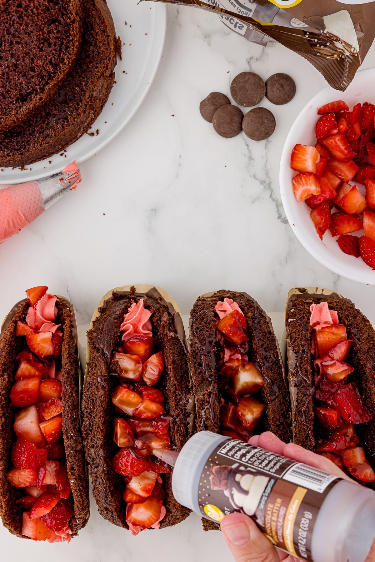 four chocolate cake tacos filled with strawberries on a white marble countertop