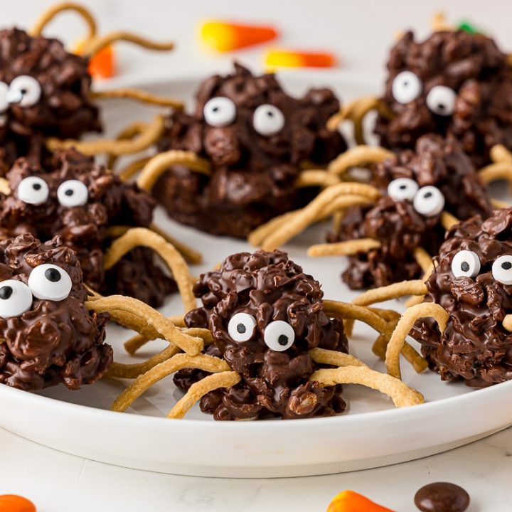 no bake chocolate spider cookies on a white plate with candy corn on the white countertop