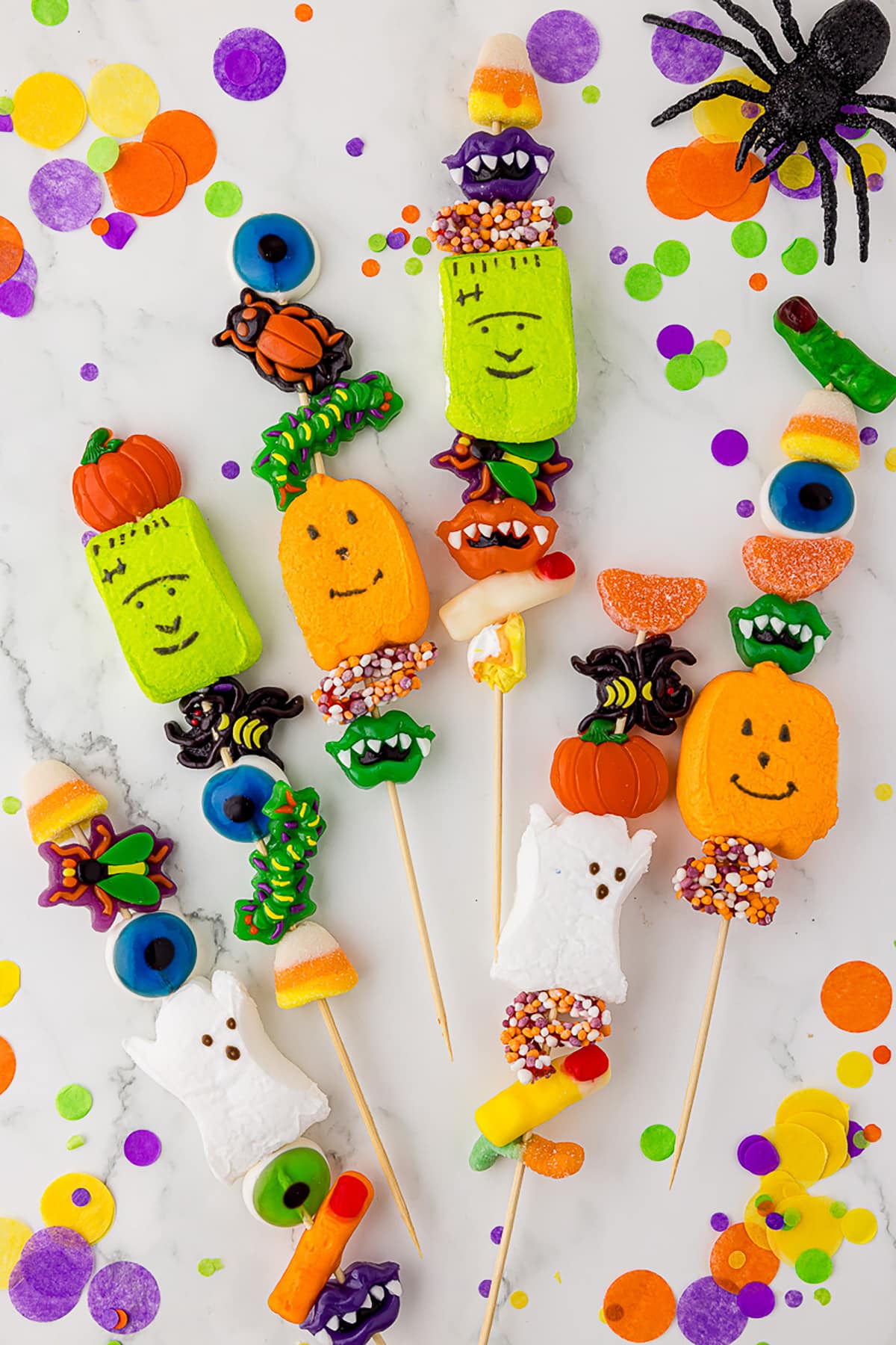 6 halloween candy kabobs on a white countertop with green, yellow, orange, and purple confetti