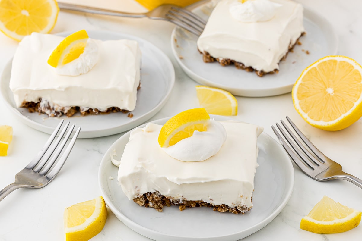 Lemon pie plated on the counter with silver forks and lemon slices