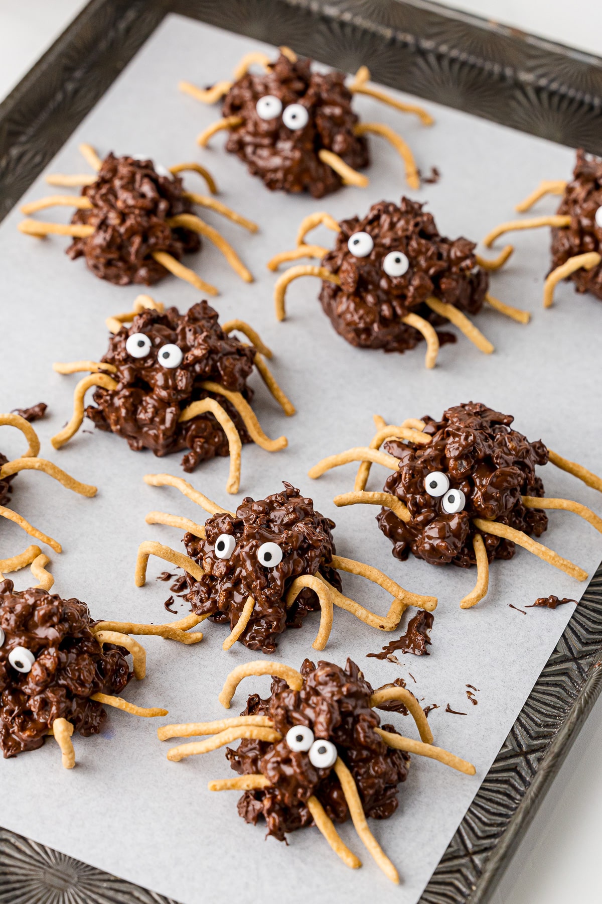 several halloween no bake spider cookies on a cookie sheet that is lines with parchment paper.