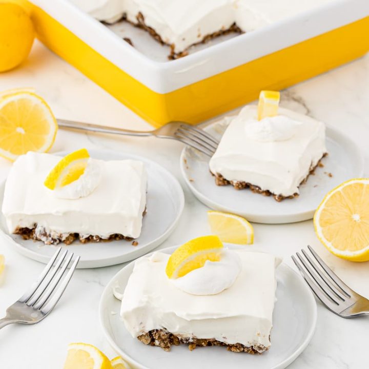 Plated lemon pie pieces on white plates with forks and lemons