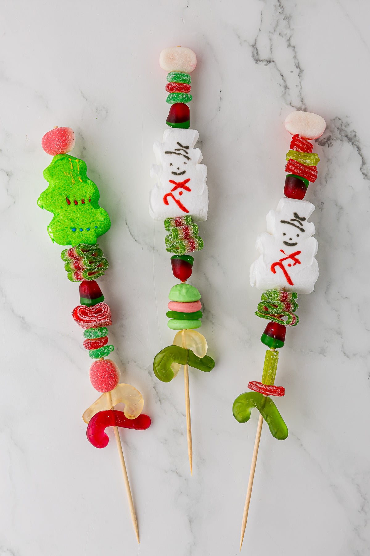 Three candy kabobs on a white countertop
