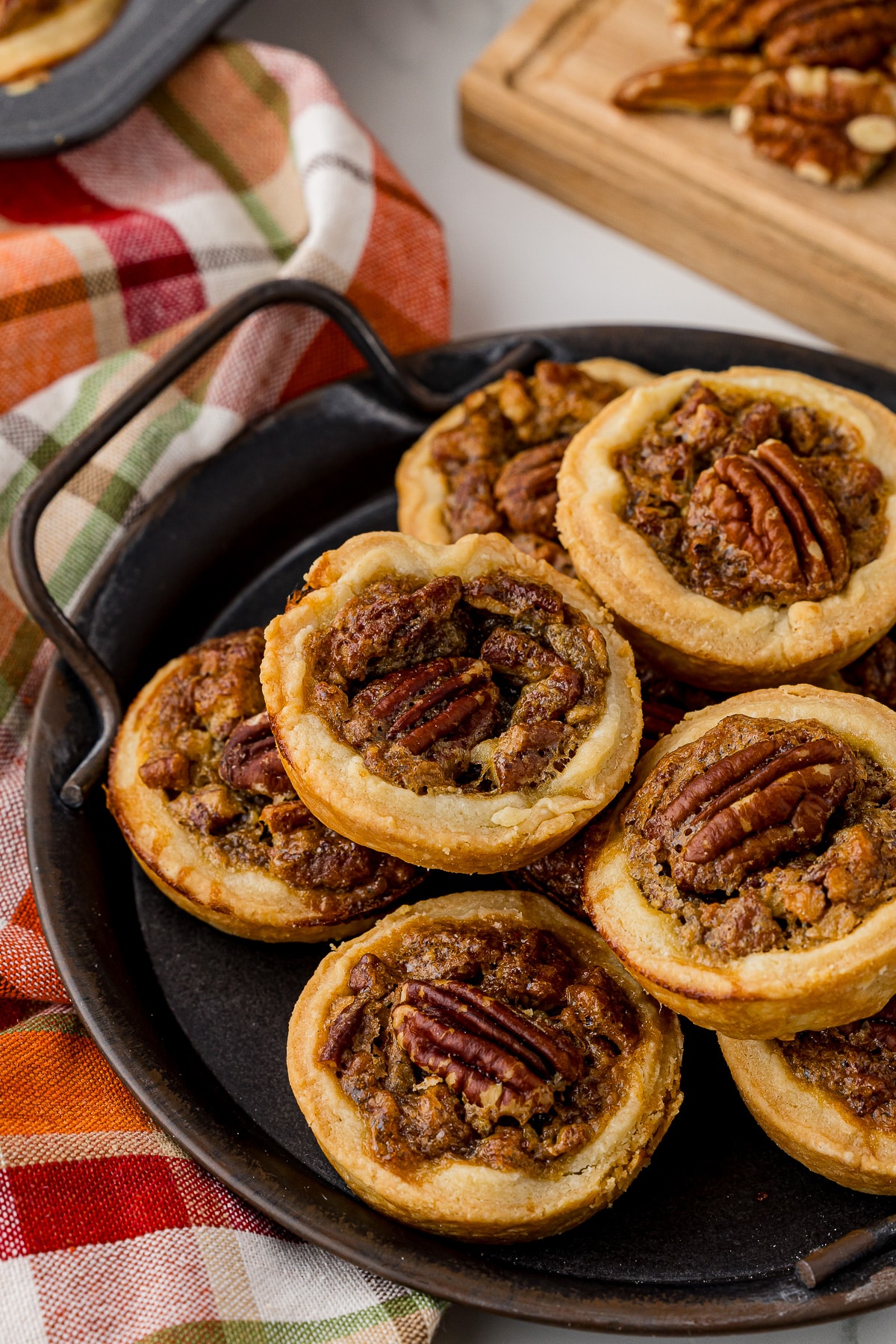 Stack of mini pecan pies on a metal serving dish. 