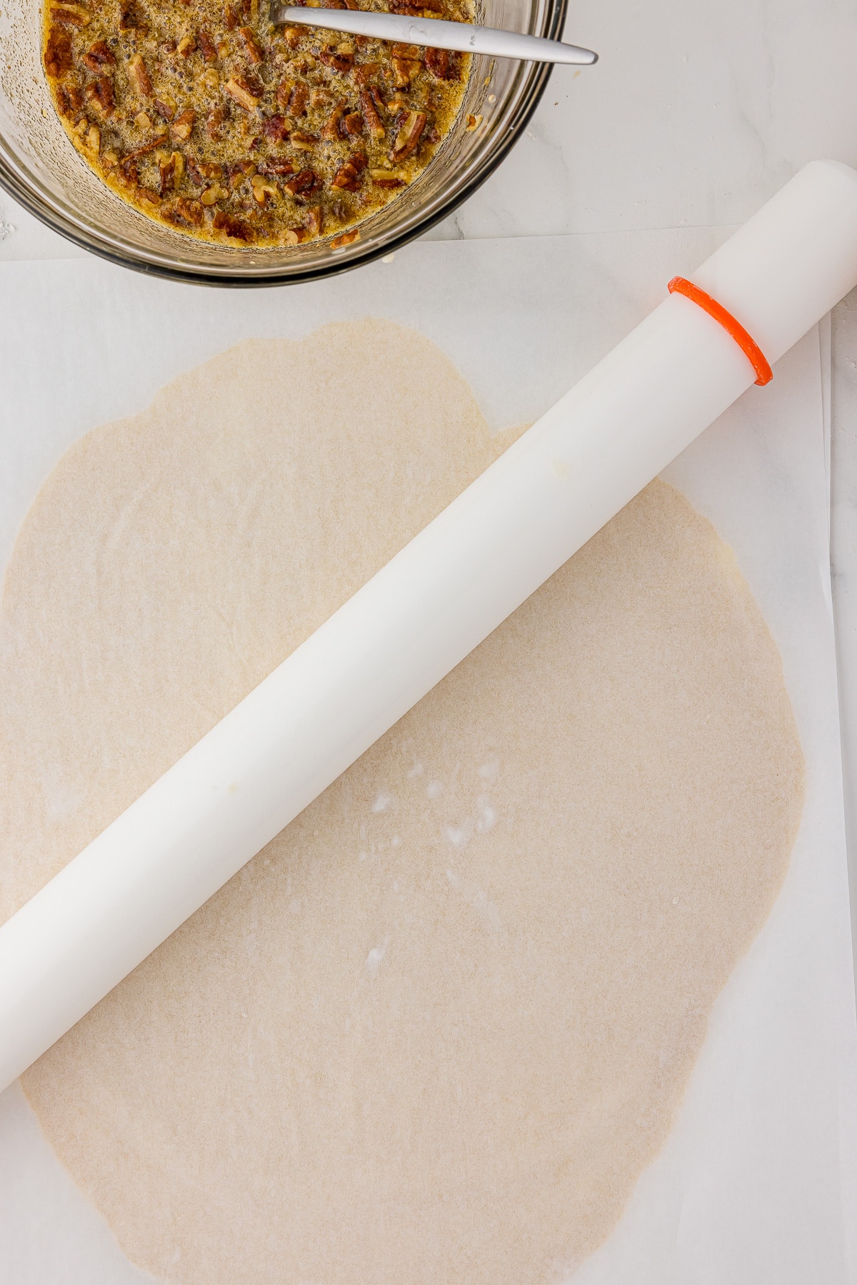 Wilton fondant rolling pin on a parchment sheet with dough inside.