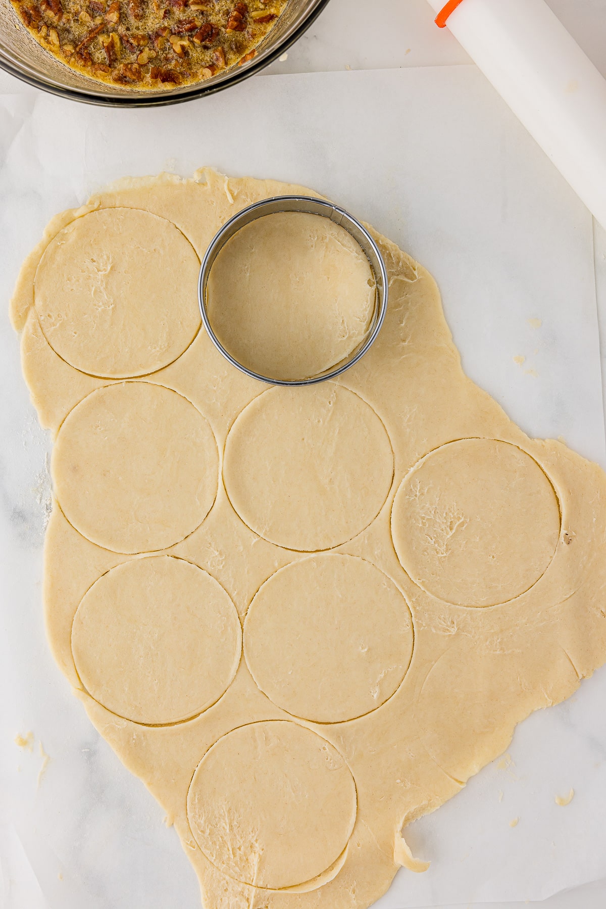 Round cookie cutter cutting dough into circles. 