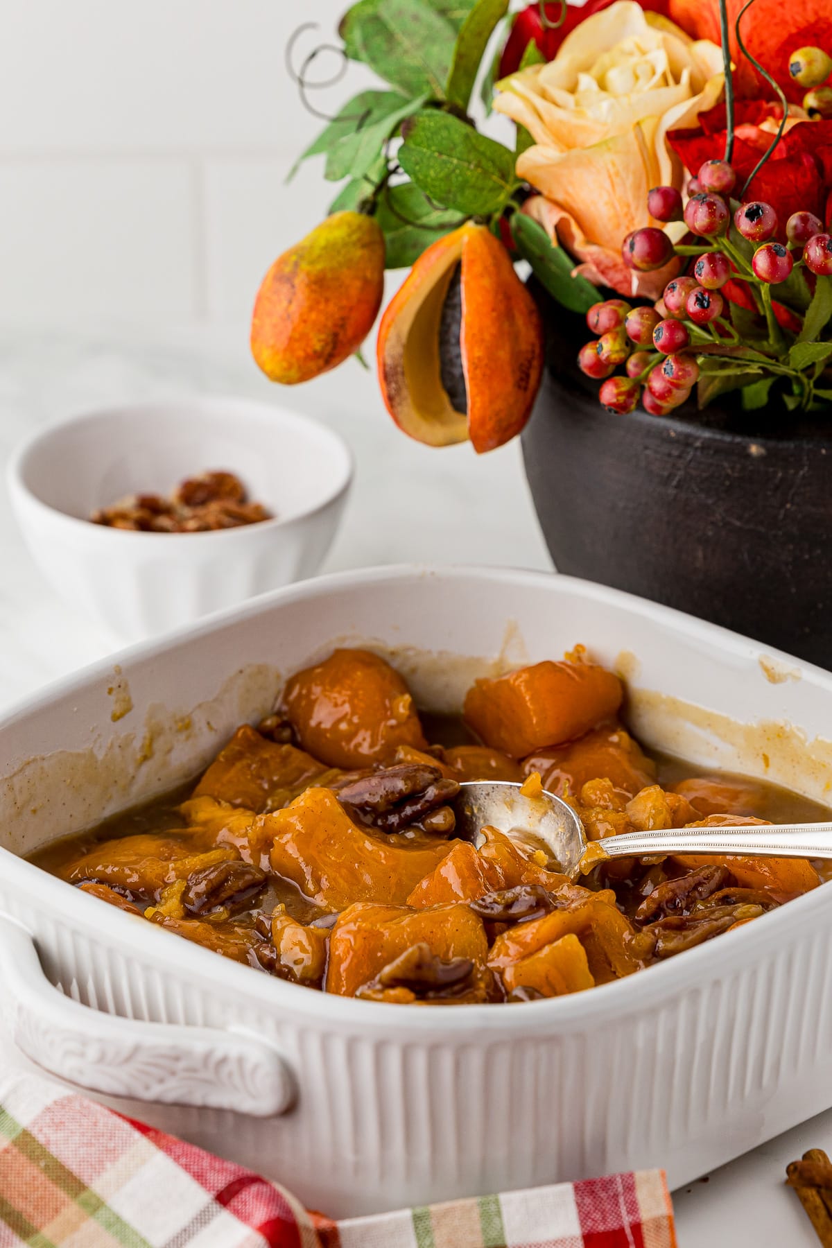 apricot sweet potato casserole on a white countertop with an autumn flower bouquet on a white countertop