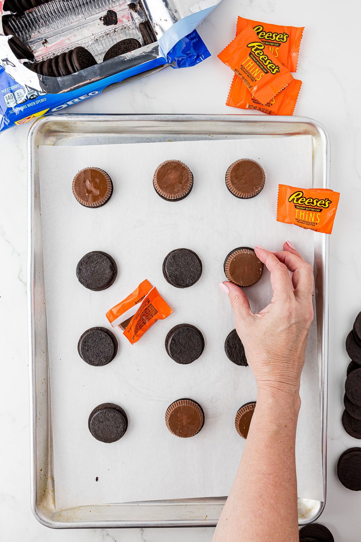 12 reese's oreos on parchment paper with oreos and reese's thins in wrappers on a white counter