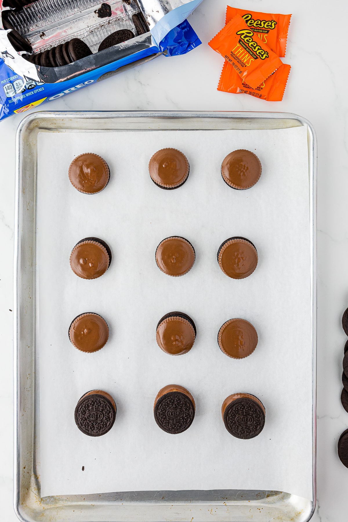 12 reese's oreos on parchment paper with oreos and reese's thins in wrappers on a white counter