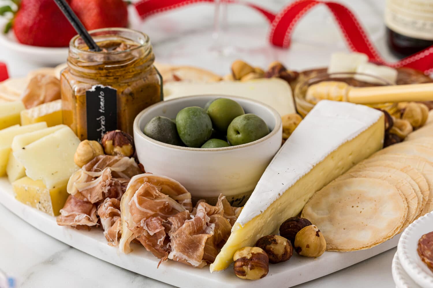 Close up of party food on a party charcuterie board platter including meats, cheese and crackers and olives