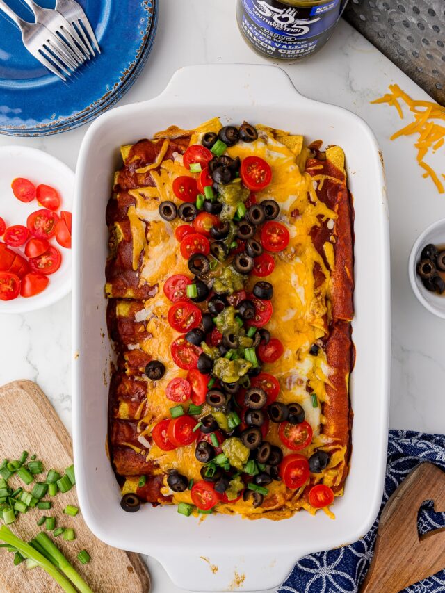 taquito casserole in a white 9x13 with blue plate and forks, green chili, shredded cheddar cheese, sliced olives, sliced tomatoes, blue dishcloth on a white countertop