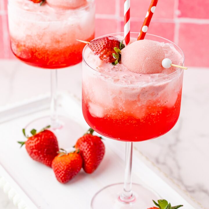 Two pink drinks on a white platter with strawberries, strawberry Yasso mochi, and colorful straws